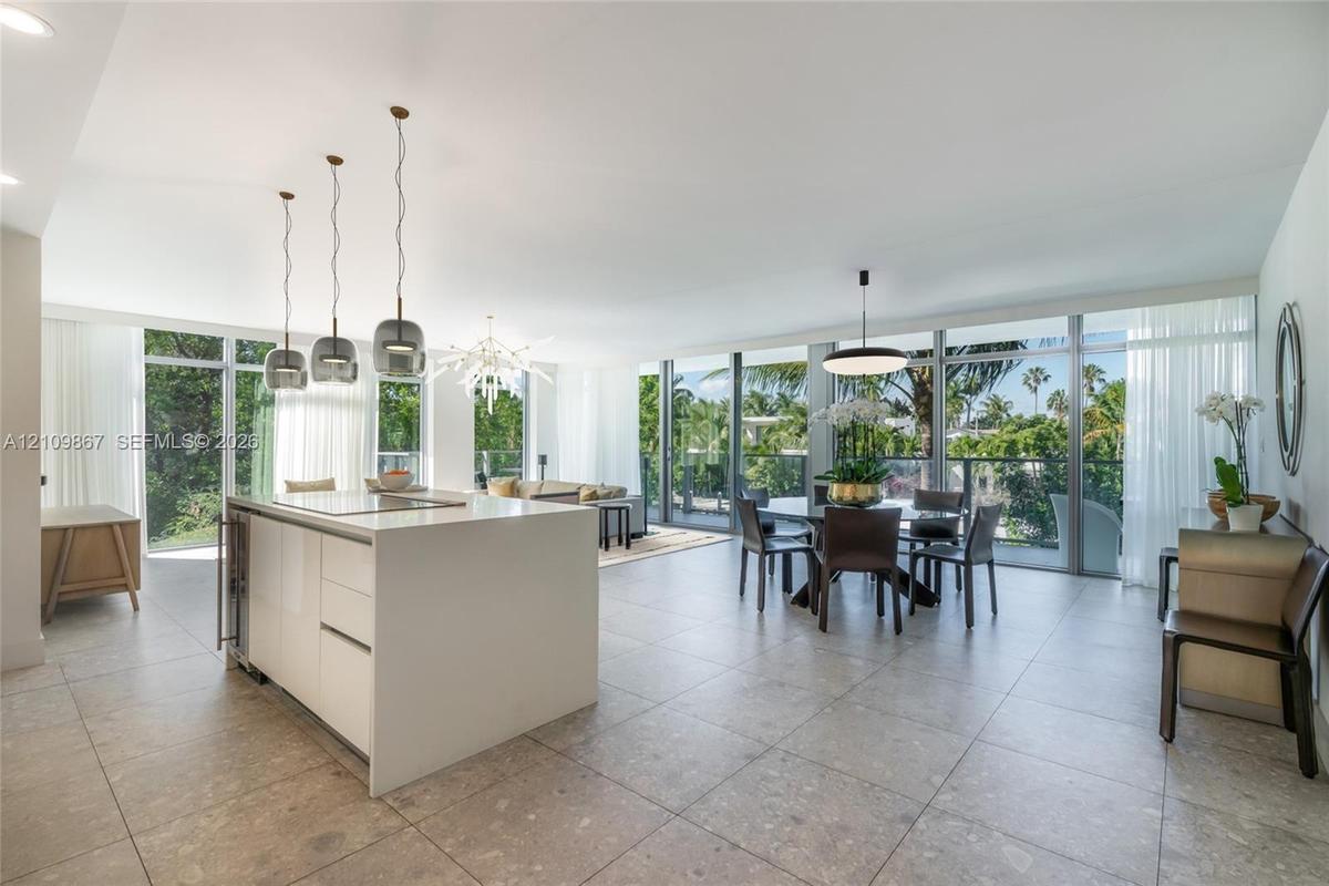 Open-concept interior featuring large-format tile flooring, floor-to-ceiling windows, white center island with solid-surface countertops, and contempo