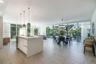 Open-concept interior featuring large-format tile flooring, floor-to-ceiling windows, white center island with solid-surface countertops, and contempo