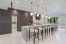 Kitchen featuring a waterfall-edge center island, two-tone custom cabinetry, stone-style countertops, professional-grade stainless steel appliances, a