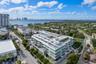 Multi-story residential building featuring a rooftop swimming pool, expansive glass-railed balconies, and extensive exterior landscaping