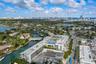 Aerial perspective of a multi-story residential complex featuring a rooftop swimming pool, private balconies, and landscaped courtyard, situated on a 