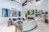 Vaulted ceiling with exposed wood beams, floor-to-ceiling stone-surround fireplace, linear electric firebox, clerestory windows, and built-in lower ca