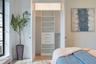 Custom-built closet featuring white cabinetry, tiered shelving, integrated drawers with metallic pulls, and dual hanging rods