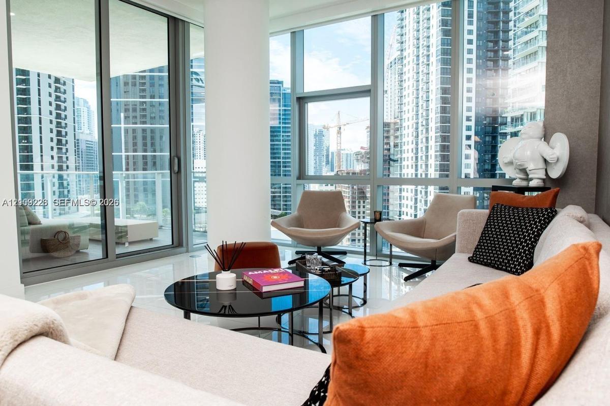 Floor-to-ceiling windows, polished stone flooring, and expansive glass balcony doors