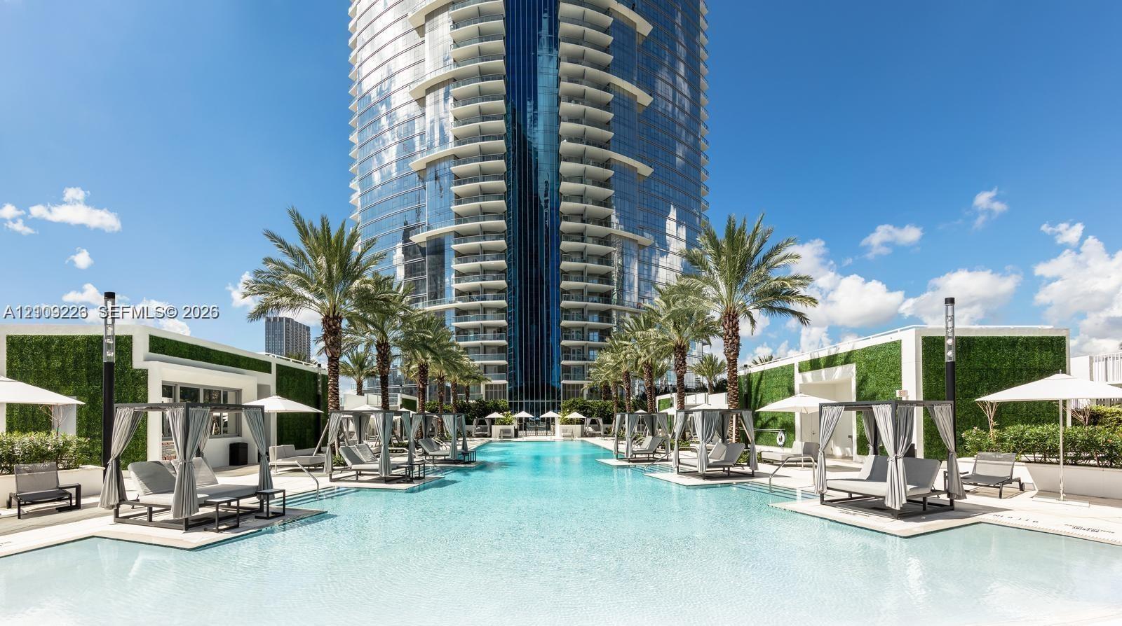 Resort-style swimming pool featuring integrated cabanas, palm tree landscaping, and vertical garden walls