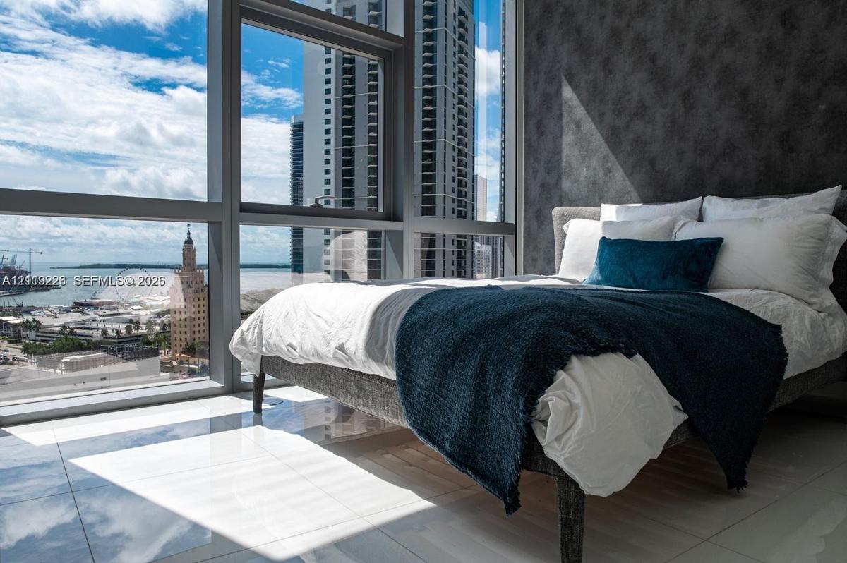 Floor-to-ceiling windows, polished tile flooring, and textured accent wall
