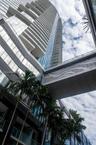 High-rise glass facade with cantilevered balconies, decorative architectural skybridge, and exterior palm landscaping