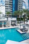 Swimming pool with integrated tanning ledge and stairs, surrounding hardscaped sun deck, private poolside cabanas, and mature palm landscaping