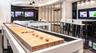 Recreational space featuring high-gloss flooring, recessed ceiling lighting, a built-in media wall with integrated displays, and floor-to-ceiling glas