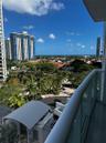 Private balcony featuring a glass-panel railing and expansive urban and ocean scenery