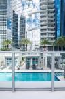 Swimming pool featuring concrete decking, perimeter cabanas, and glass-paneled balcony railing
