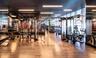 Fitness center featuring wood-finish flooring, floor-to-ceiling windows, recessed linear lighting, and full-wall mirrors
