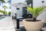Outdoor patio featuring wood-finish decking, smooth stucco exterior walls, hardscaped stone pathways, and integrated cylinder landscape lighting