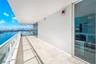 Oversized wrap around balcony glass panel railings, and full-height sliding glass doors