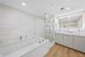 Master bathroom featuring a frameless glass-enclosed shower, a deep soaking tub with stone-finish surround, a dual-sink vanity with comfort height cab