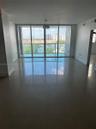 Floor-to-ceiling glass windows, polished tile flooring, glass balcony railing, and natural lighting
