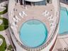 Curved outdoor deck featuring a tiled terrace, circular swimming pool with built-in stairs, secondary rectangular pool, and a glass panel perimeter ra