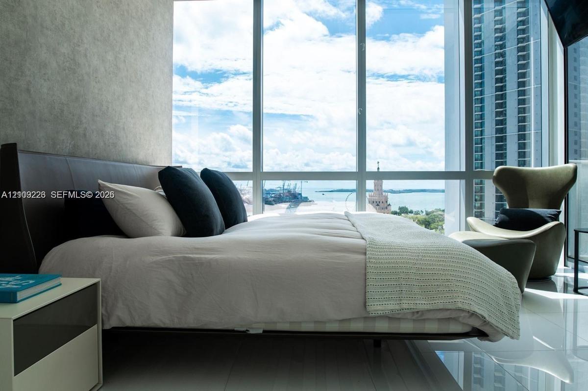 Floor-to-ceiling windows featuring panoramic maritime and urban scenery, complemented by polished tile flooring and a textured accent wall