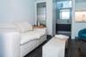 Kitchenette featuring white cabinetry, integrated stainless steel refrigerator, and under-cabinet lighting