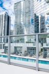 Swimming pool with a glass panel railing, paved sun deck, and structural cabana-style enclosures