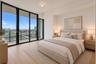 Floor-to-ceiling glass sliding doors, private balcony, wood-finish flooring, and neutral wall tones