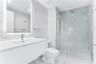 Bathroom featuring a floating vanity with a smooth surface, wall-to-wall mirror with integrated lighting, large-format stone-patterned wall tile, and 