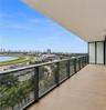 Covered balcony featuring wood-finish flooring, glass panel railing with dark metal framing, and floor-to-ceiling glass door access