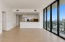 Open-concept interior featuring floor-to-ceiling glass panel walls, wood-finish flooring, white flat-panel cabinetry, stainless steel appliances, and 