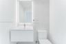 Modern floating vanity with a seamless sink, LED-backlit mirror, and large-format porcelain tile wall cladding