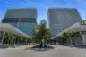 High-rise residential towers featuring glass-curtain facades, expansive balconies, integrated ground-level retail, and professionally landscaped paved