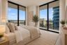 Floor-to-ceiling windows with dark framing, metal balcony railings, and neutral flooring