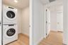 Utility space featuring a stacked white laundry unit, recessed ceiling lighting, and wood-finish flooring