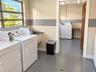 Utility room featuring jalousie windows, a deep basin sink, and resilient epoxy-coated flooring