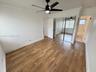 Room featuring wood-finish flooring, a matte black ceiling fan with integrated lighting, crown molding, and floor-to-ceiling mirrored sliding closet d
