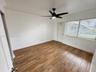 Wood-finish tile flooring, neutral walls, crown molding, multi-blade ceiling fan with integrated light, and horizontal window blinds