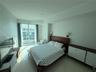 Floor-to-ceiling glass door, polished tile flooring, wall-mounted bedside light fixtures, and recessed architectural ceiling detailing