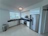 Kitchen featuring high-gloss white cabinetry, stainless steel appliances, dark stone countertops, polished tile flooring, and a crystal flush-mount li