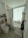 Bathroom featuring a soaking tub, neutral tile flooring, and wall-mounted metal hardware