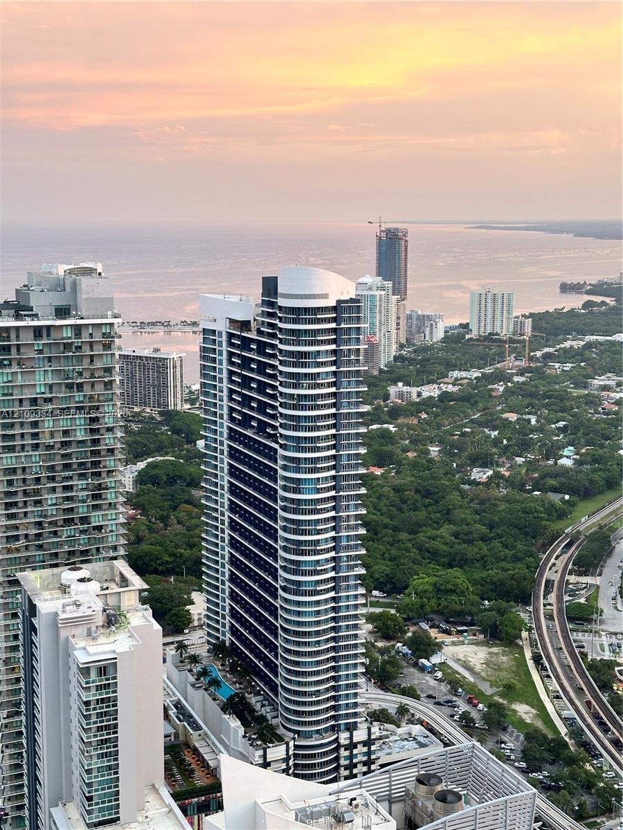 High-rise residential tower featuring a curved glass facade and a multi-level swimming pool terrace