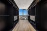 Custom walk-in closet featuring floor-to-ceiling dark cabinetry, integrated shelving, drawer units, wood-finish flooring, and full-height window panel