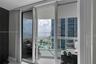 Floor-to-ceiling sliding glass door system, balcony with white metal railing, and ocean horizon backdrop