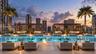 Rooftop pool deck featuring an expansive stone-tile deck, integrated aquatic pool, dual slatted-wood pergolas, and perimeter glass railings