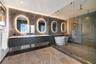 Bathroom featuring a floating double vanity with a light-toned countertop, four wall-mounted illuminated oval mirrors, a freestanding soaking tub, and