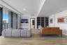 Open-concept living space featuring wood-finish flooring, floor-to-ceiling glass sliding doors, built-in floor-to-ceiling shelving, and a wall-mounted