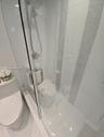 Glass-enclosed shower featuring large-format wall tile, decorative vertical mosaic accent inlay, and adjustable chrome shower head