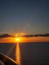 Exterior railing overlooking an expansive water horizon at sunset