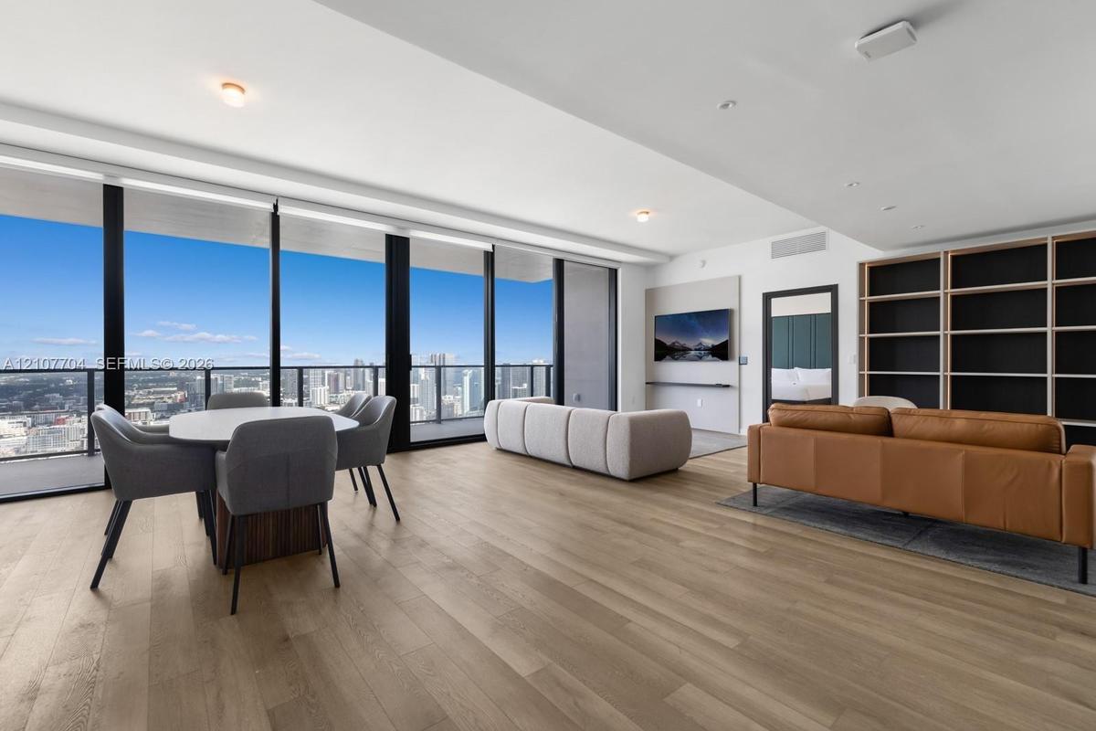 Floor-to-ceiling windows, wood-finish flooring, built-in shelving, recessed lighting, and a private balcony