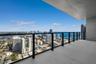 Covered balcony with large-format tile flooring and sleek black metal railing featuring transparent glass panels