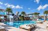 Rooftop swimming pool featuring large-scale sculptural elements, limestone-finish decking, integrated palm tree landscaping, and overhead wood-slat st