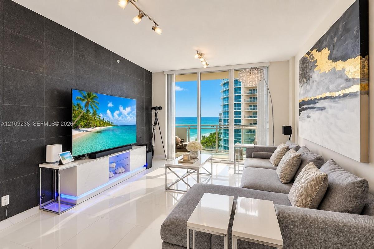 Living area featuring a large format dark tile accent wall, polished tile flooring, glass sliding doors, and adjustable track lighting
